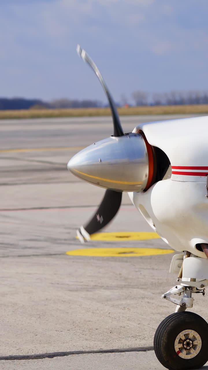 Front part of white aircraft with red lines. Little plane with rotating propeller. Vertical video