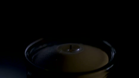 slow motion macro footage of a white candle on a dark background