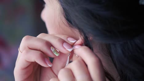 woman putting on earrings