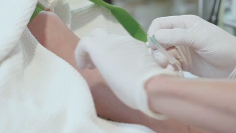 experienced doctor drawing blood taking blood sample of female calm patient, inserting hollow butterfly needle syringe into vein after disinfecting arm