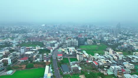 aerial forward flyover miaoli city with green fields in taiwan during cloudy morning