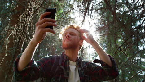 Guy-fixing-hairstyle-before-selfie-on-smartphone.-Hiker-taking-selfie-on-phone