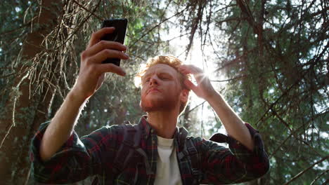 guy fixing hairstyle before selfie on smartphone. hiker taking selfie on phone