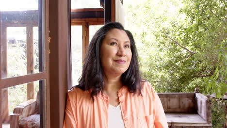 smiling senior woman in orange shirt enjoying peaceful moment on porch