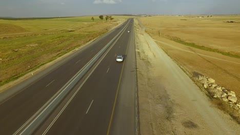 Flying-above-countryside-road-through-beautiful-desert-scenery-in-sunny-summer