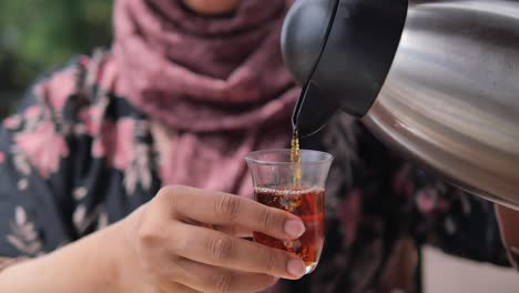 woman pouring tea into a glass