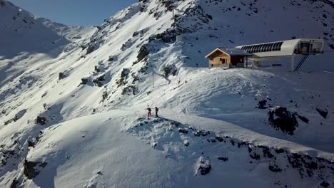 esquiadores en la cima de la montaña junto a la terminal del telesilla val thorens - toma aérea ascendente dronie
