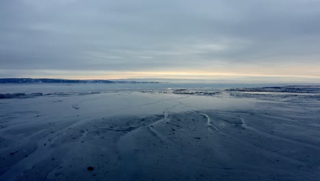 Aerial-shot-over-the-water-of-the-shore-of-a-beach-in-winter-in-Charlevoix