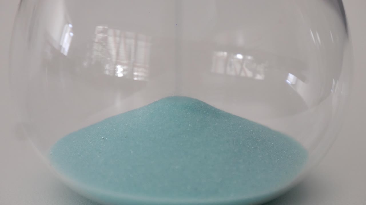 primer plano de la parte inferior de un reloj de arena mientras se acumula la arena