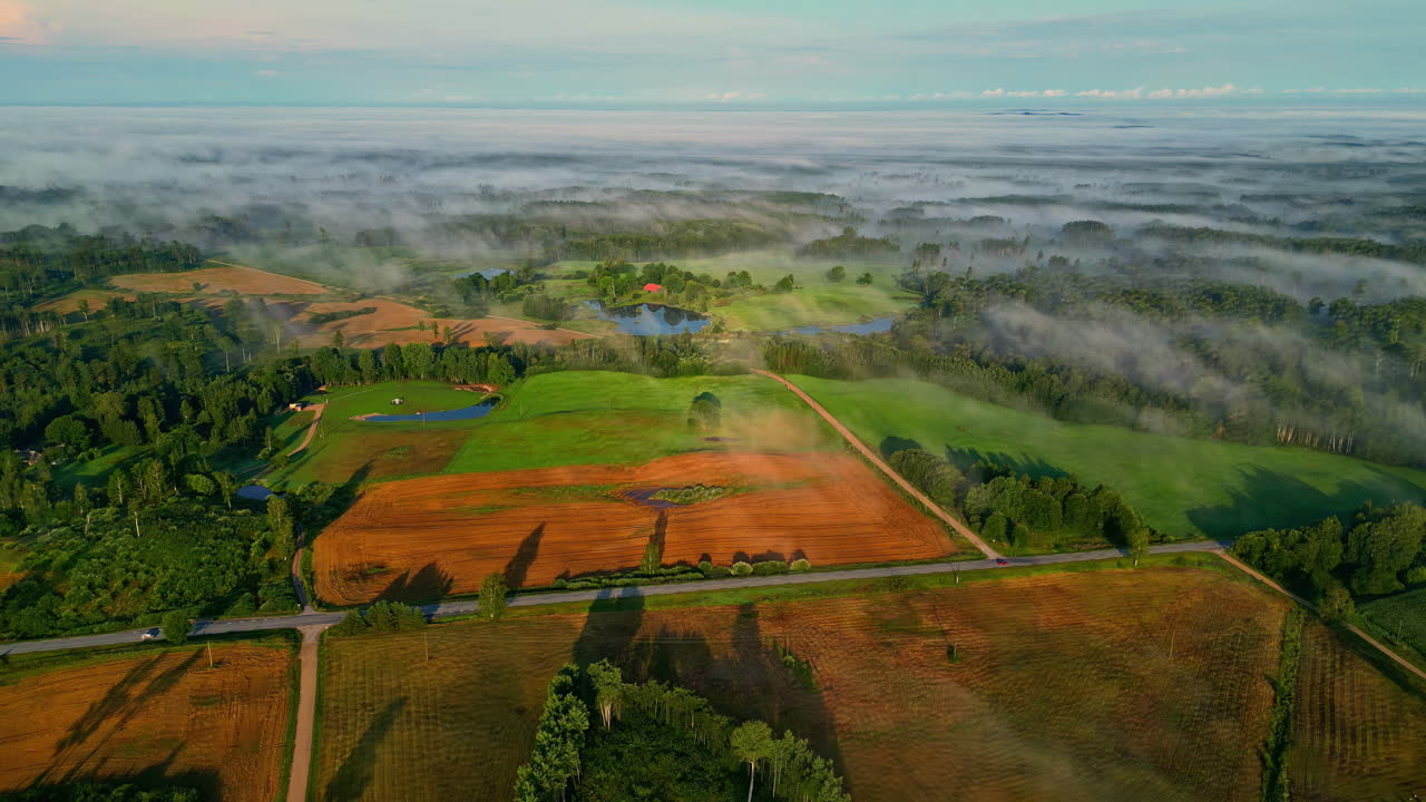 Glowing farmland landscape with light mist above, aerial view