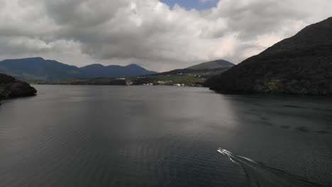 seguimiento de tiro aéreo inclinado hacia arriba de lancha rápida en el lago con montañas en la distancia