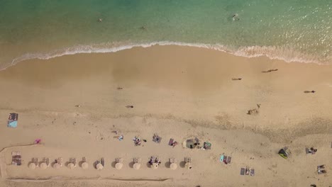 Luftaufnahme-Eines-Sandstrandes-Auf-Der-Kanarischen-Insel-Fuerteventura-In-Spanien-Mit-Sonnenschirm-Und-Menschen,-Die-Sich-Sonnen