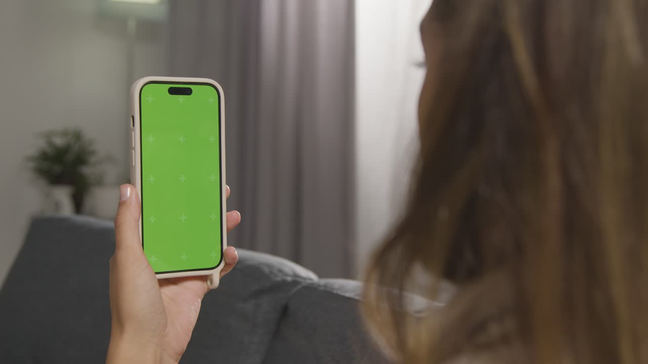 sobre el hombro de la mujer usando un teléfono móvil de pantalla verde