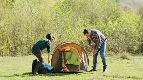 hermosa esposa ayudando a su marido a poner la tienda de campamento