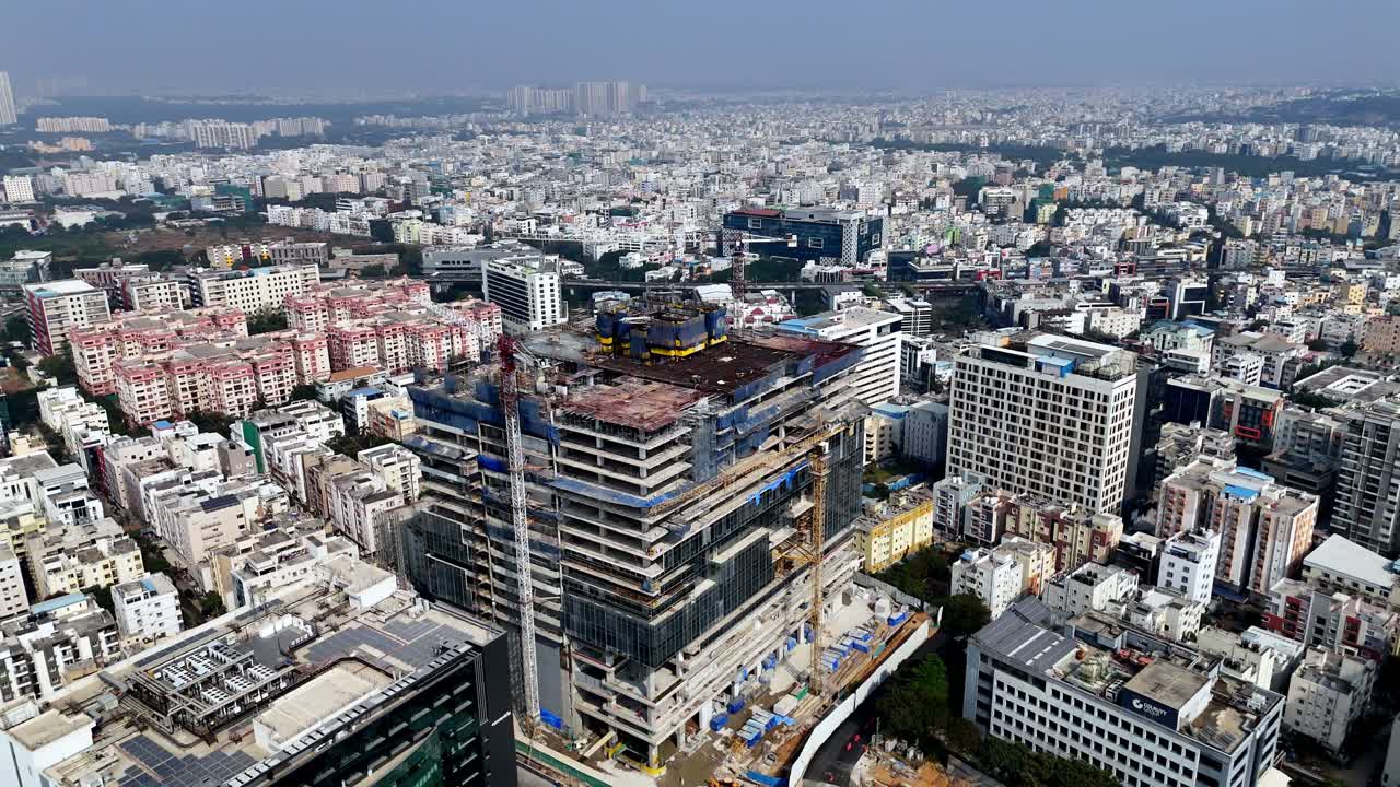 Entorno urbano denso en transición a ciudad moderna. Expansión urbana en curso; este impresionante video de dron captura el auge de la construcción en Hyderabad, donde emergen oficinas modernas sobre un bullicioso paisaje urbano.