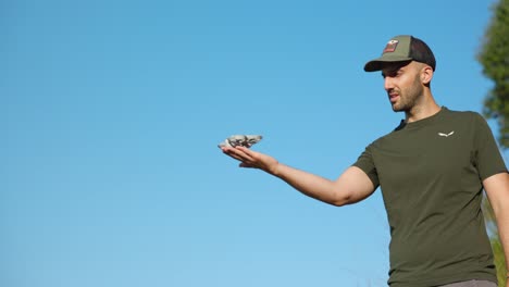 a man skillfully launches a dji neo drone from his palm, set against a bright blue sky. captures innovation and technology in action.