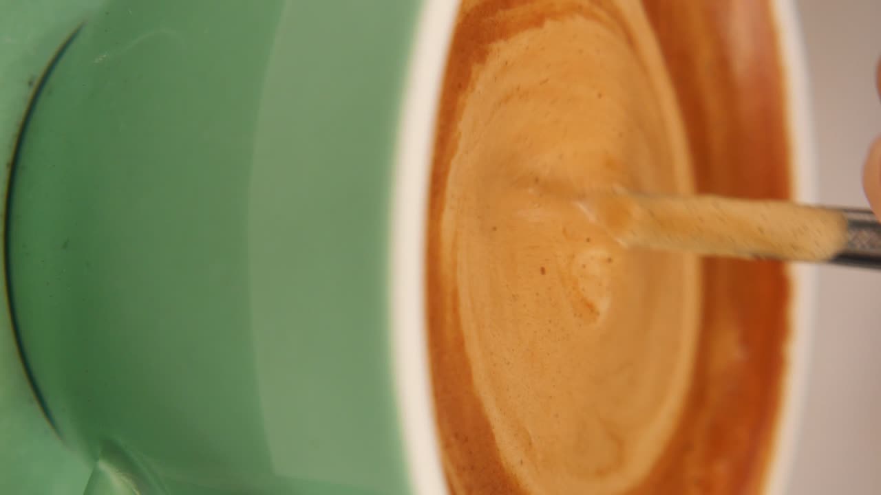 Close-up of coffee being stirred in a green cup