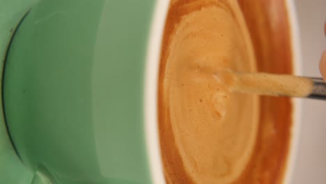 close-up of coffee being stirred in a green cup
