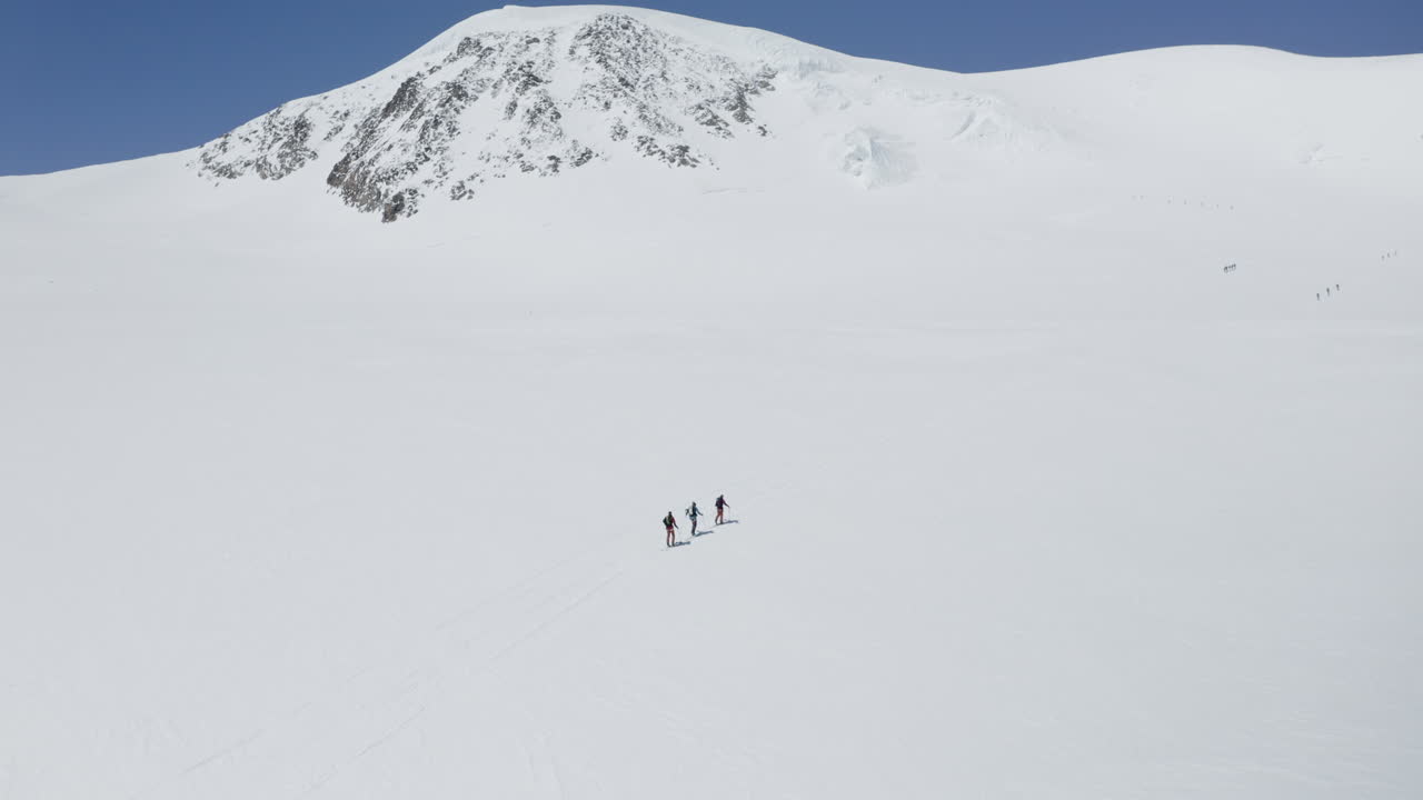 Two freeriders ski tour up the majestic Alphubel with their guide, then descend through glacial terrain surrounded by crevasses and seracs in the high alpine landscape of Saas-Fee