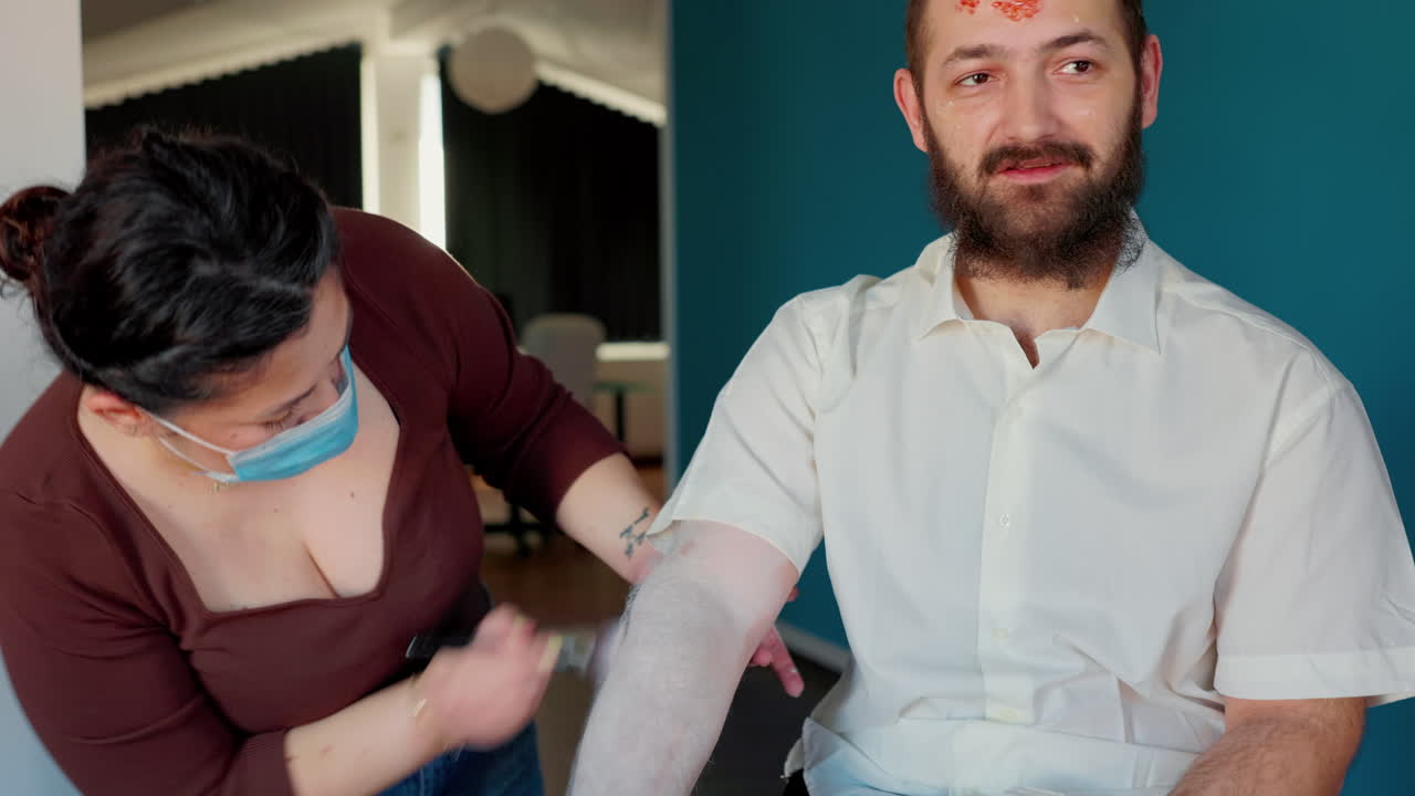 Young adult actor getting ready for zombie role while make-up artist preparing him for video shooting