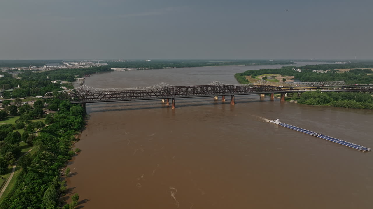 memphis tennessee antena v38 sobrevuelo del río mississippi vista panorámica capturando el puente harahan y el parque junto al río arkansas con un remolcador empujando una barcaza en la vía fluvial - filmada con cine mavic 3 - mayo de 2022