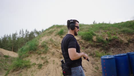 bearded masculine male walk and insert magazine in handgun, fire shots