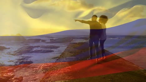 animación de la bandera de colombia sobre una pareja afroamericana en la playa