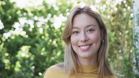 Portrait-of-happy-biracial-woman-with-blonde-hair-in-garden,-slow-motion,-copy-space