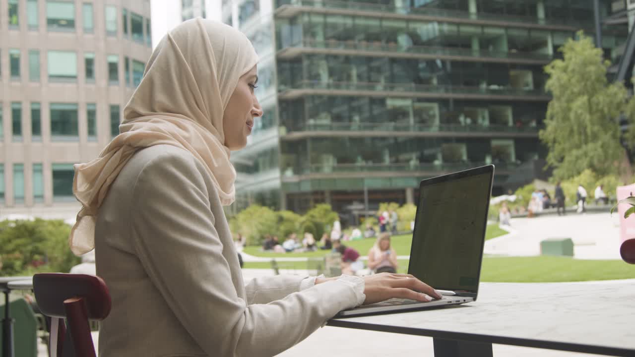 Muslim Businesswoman Sitting Outdoors In City Gardens Working On Laptop 1