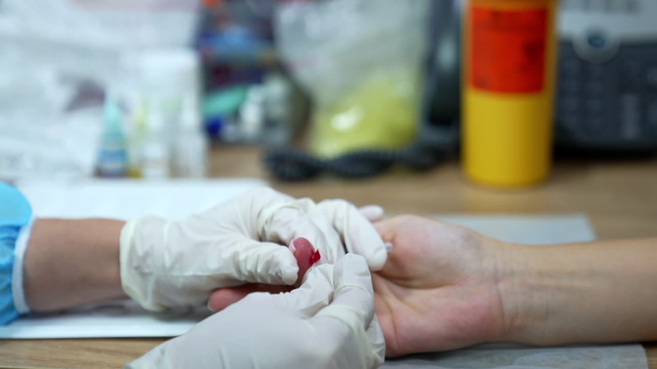 Little red cut on the finger of a female hand. Gloved hands using tool to get some blood for the test. Close up.