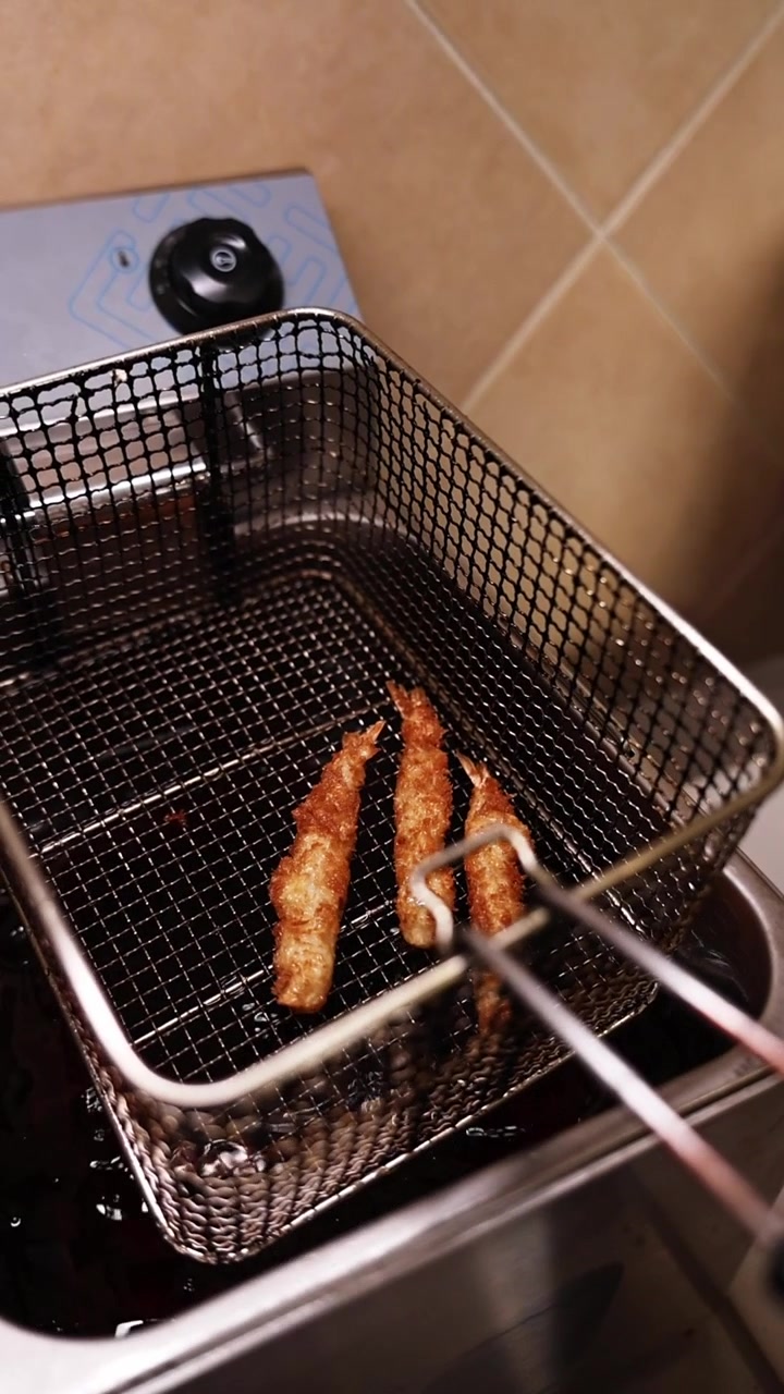 Gyldenbrune friturestegte rejer drypper af i en friturekurv