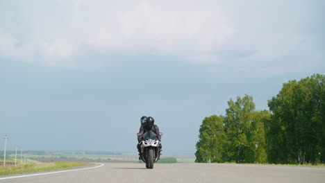 Cyclist-with-passenger-rides-motorcycle-at-countryside