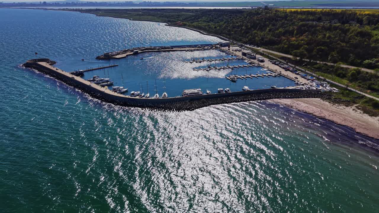 Kystudsigt over en havn med både i klart vand om dagen.