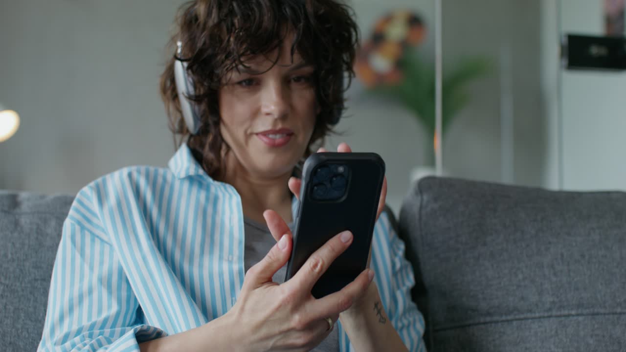 mujer relajándose en el sofá con auriculares y teléfono
