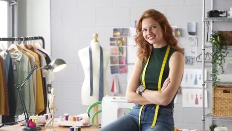 Portrait-Of-Female-Student-Or-Business-Owner-With-Tape-Measure-Working-In-Fashion-Sitting-On-Desk