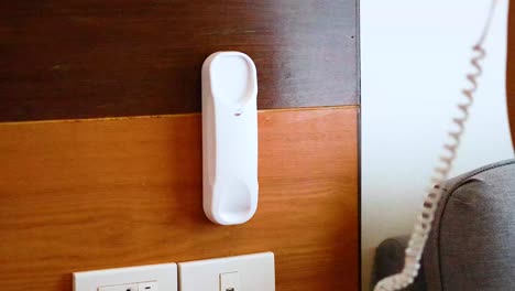 hand picks up wall-mounted phone receiver