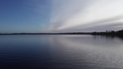 low level drone flying over lake in denmark, scandinavia - dolly in shot