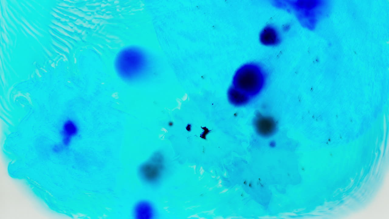 하 바탕에 물에 떨어지는 파란색 페인트 또는 염료의 물방울의 오버헤드 으로 회전하는 다채로운 패턴을 만니다.