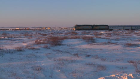 a via rail canada passenger train passes across frozen tundra