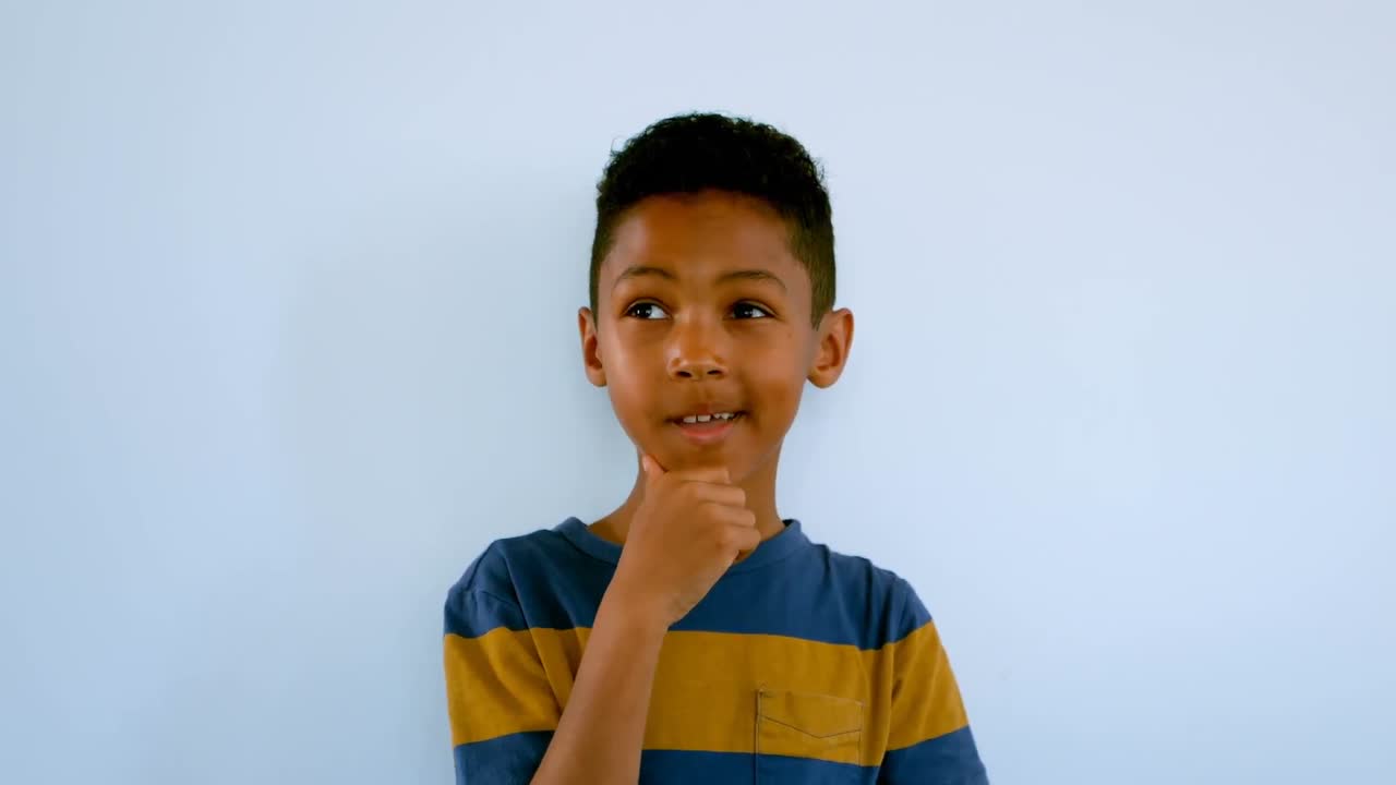 Tankefuld afroamerikansk skoledreng med hånden på hagen, der står foran en whiteboardtavle 4k
