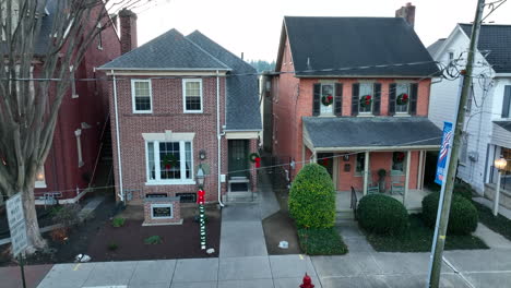 rising aerial of homes in town decorated for christmas