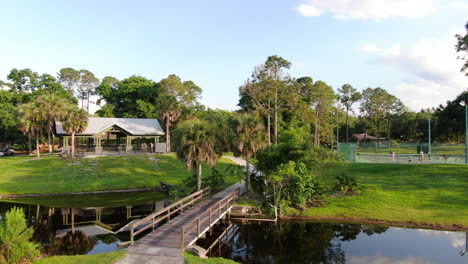 pan up from lakeside park with bridge, stream, tennis courts and gazebo