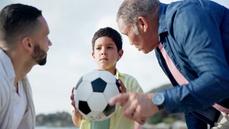 grandfather, father and son playing soccer on the beach