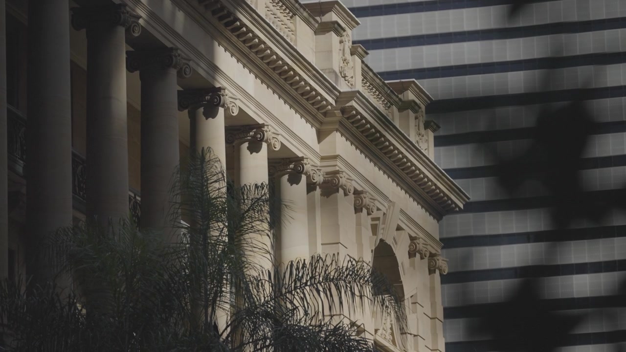 Il colonnato in arenaria di un edificio storico a Brisbane si erge accanto alla facciata in vetro a strisce di un moderno grattacielo