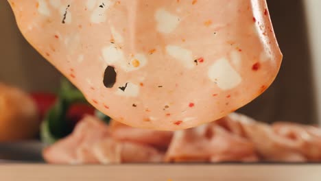mortadella ham sandwich, traditional italian focaccia filled with thin pesto slices of mortadella, served by chef man in cafe restaurant. macro of traditional italian spanish tapas antipasti.