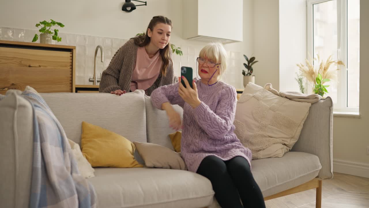 Granddaughter teaching grandmother how to use a smartphone