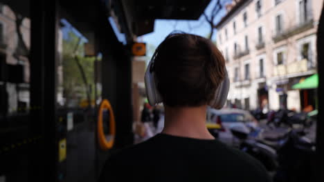 teenager walking on urban sidewalk, wearing headphones and enjoying sunny city day, experiencing musical freedom while moving through vibrant street with peaceful, carefree demeanor