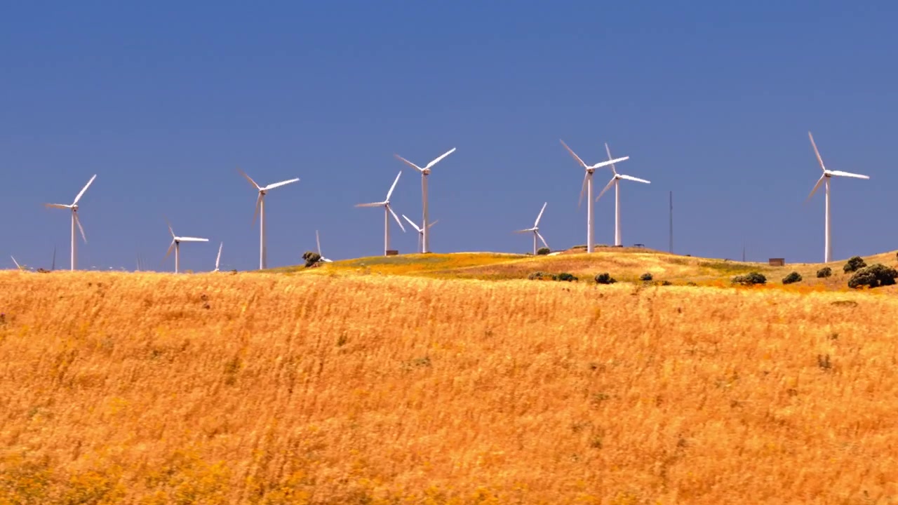 Filmato cinematografico con drone di un grande parco eolico con turbine che generano elettricità pulita e rinnovabile attraverso un paesaggio rurale. Infrastruttura energetica sostenibile a supporto della decarbonizzazione e degli obiettivi climatici