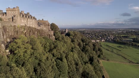 Aerial-shot-flying-easterly-along-Stirling-castle-battlements-on-a-clear-and-sunny-day,-revealing-the-church-and-graveyard