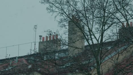 snow falls in slow motion in europe with old chimney in the background